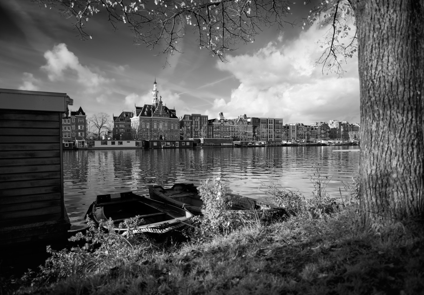 Stretch of water with boats along the shore and a row of historic buildings behind.