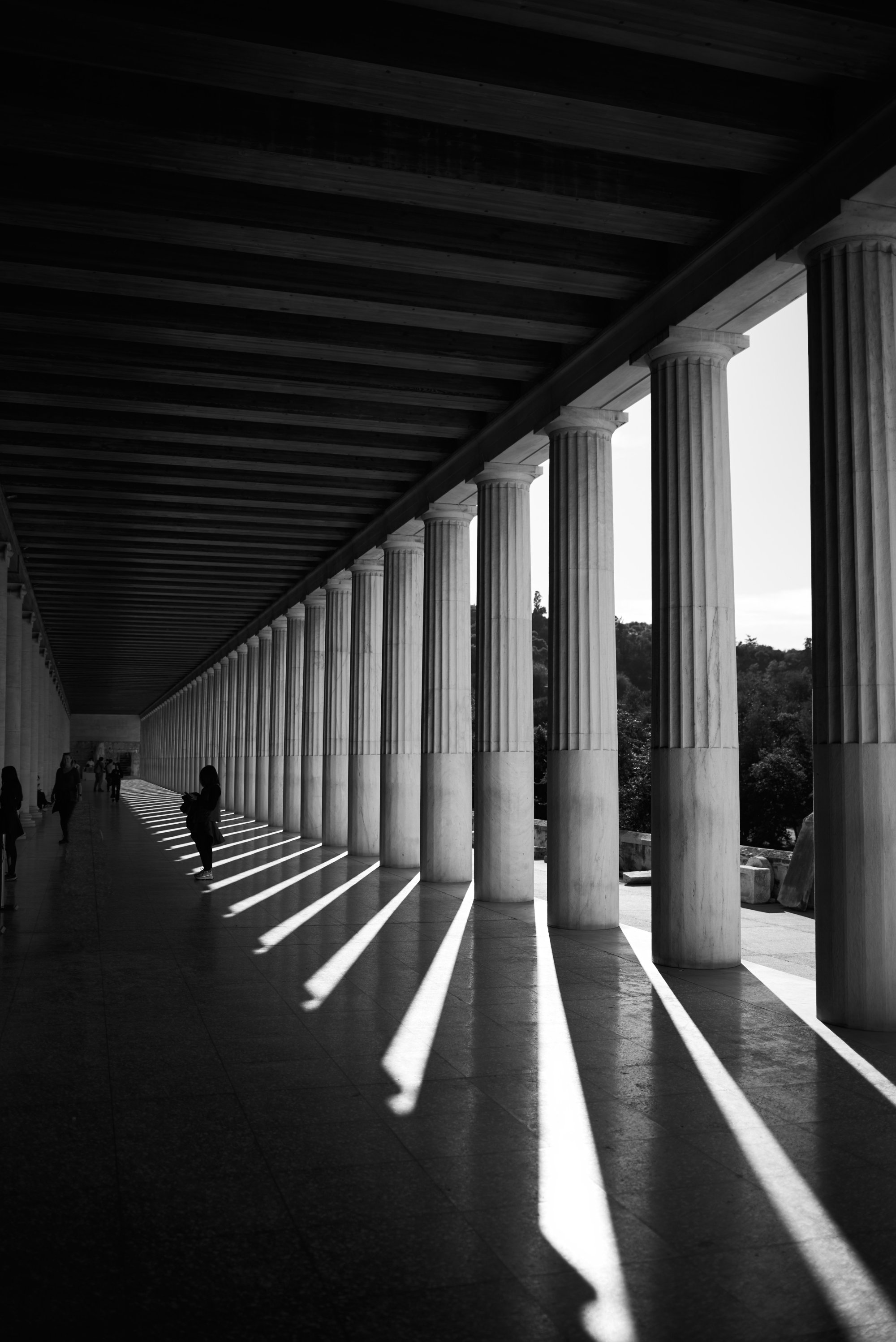 Galería de columnas con sombras alargadas sobre el suelo.