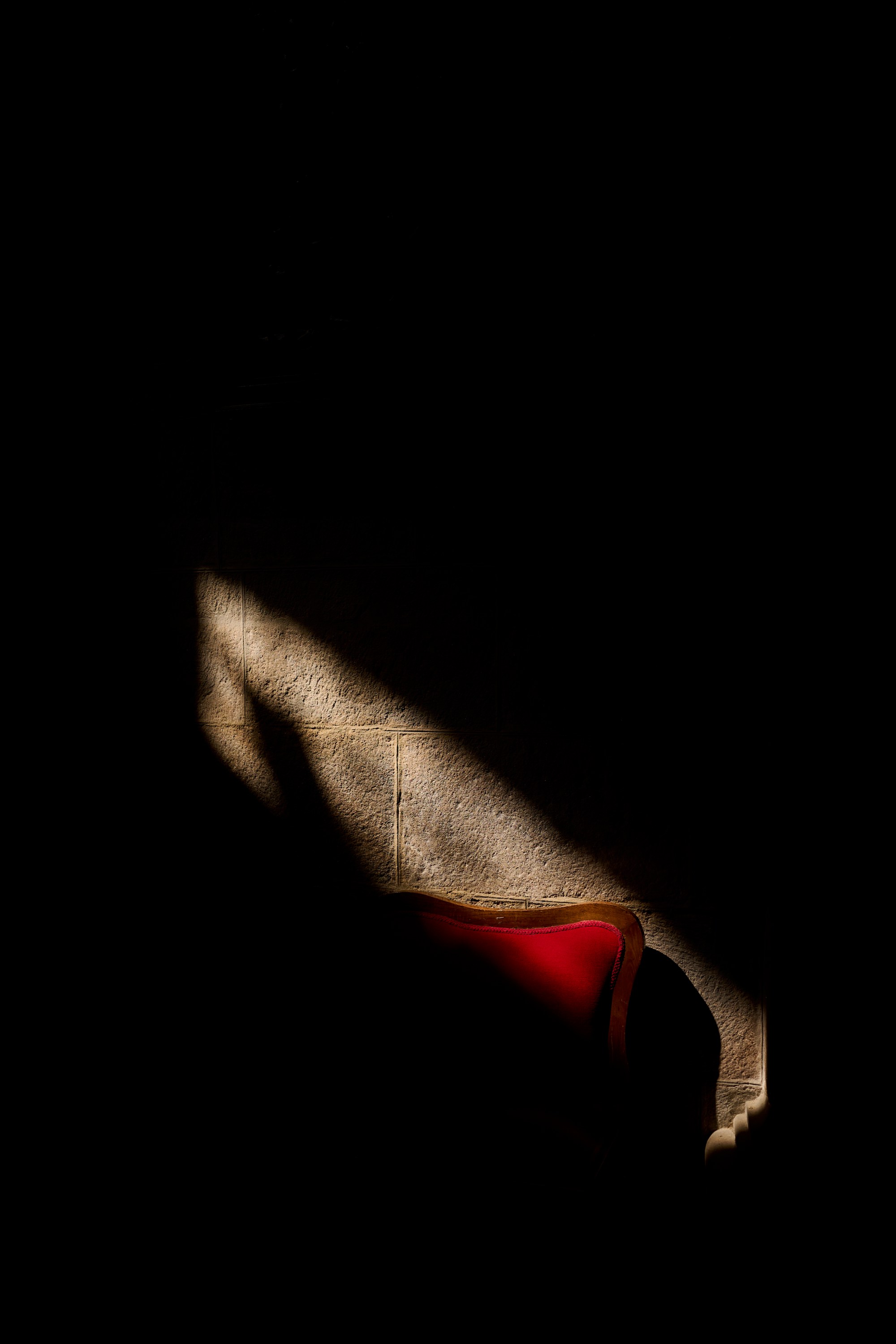Franja de luz sobre una superficie con una mancha roja, rodeada de oscuridad.