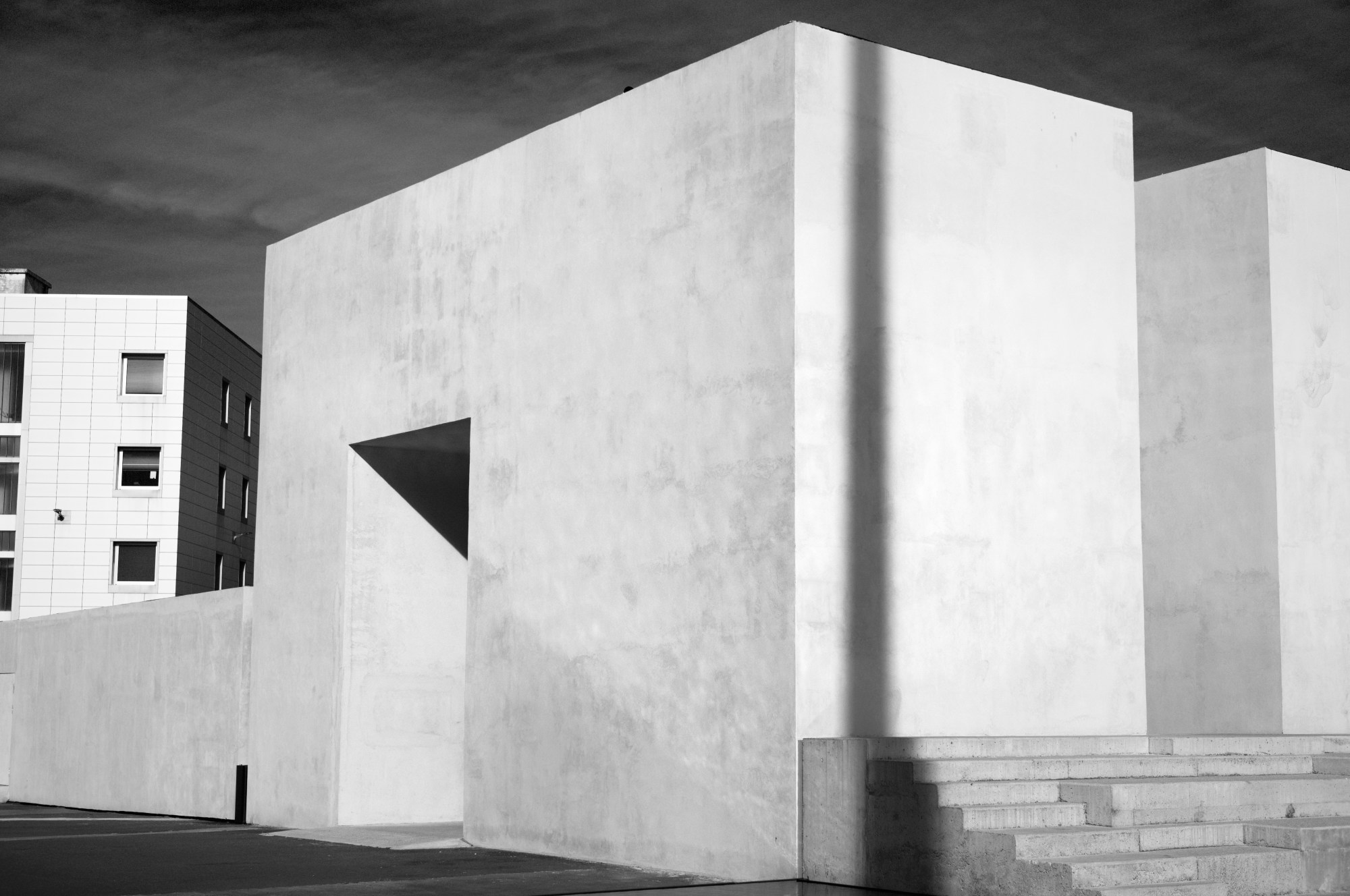 Volúmenes blancos de un edificio moderno bajo un cielo oscuro.