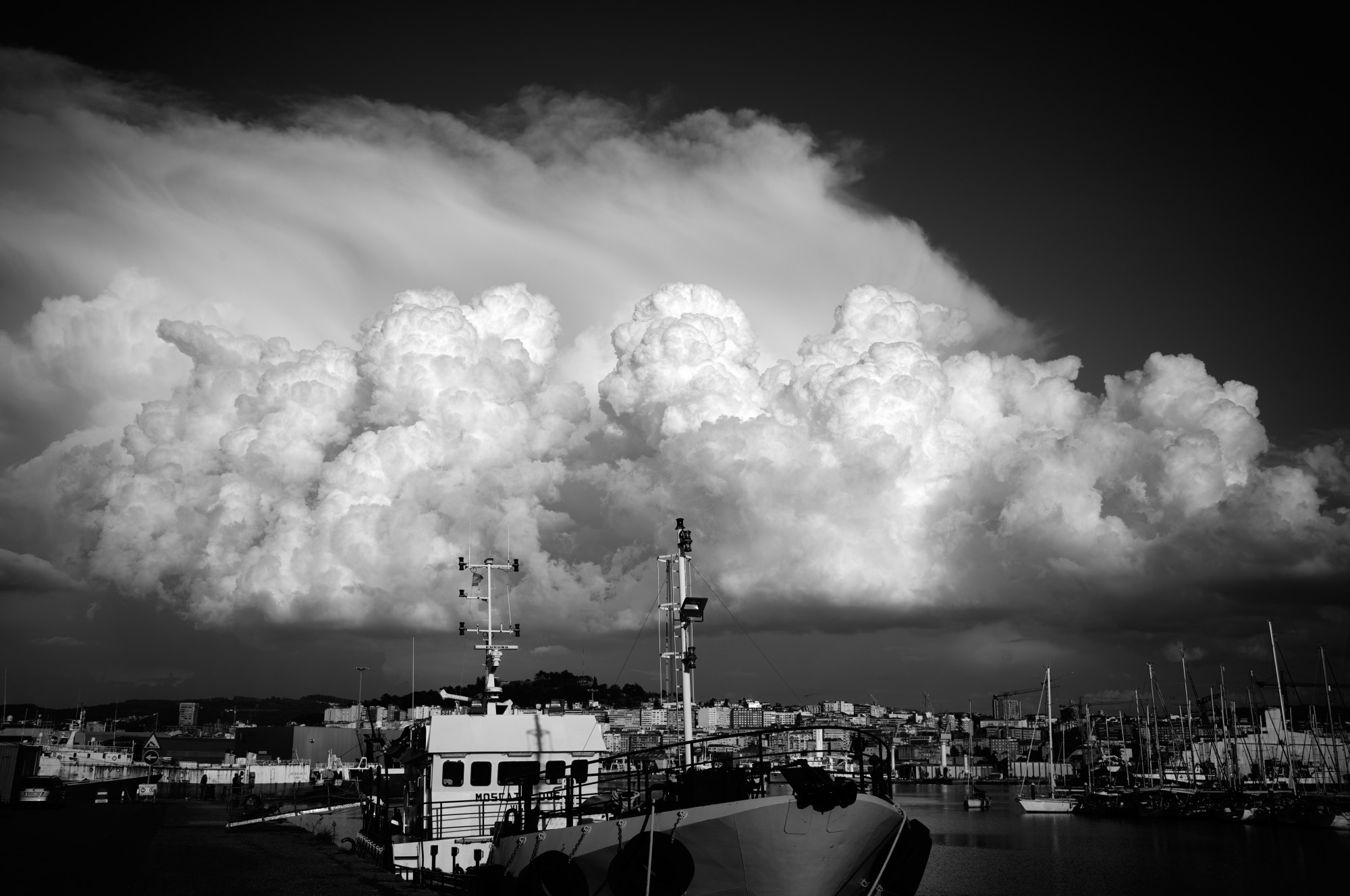 Gran nube de tormenta sobre un puerto con barcos.