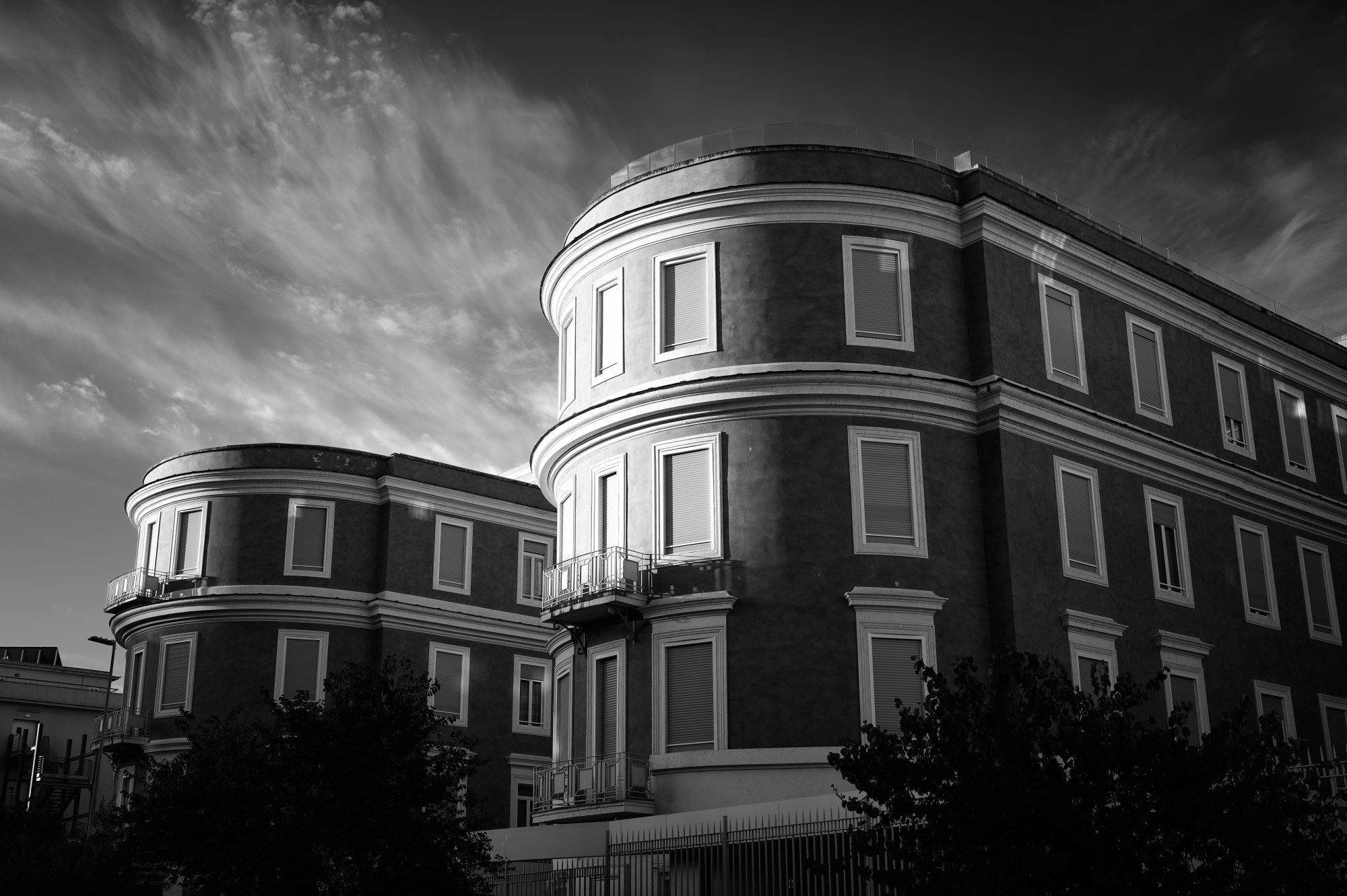 Edificio de ladrillo con fachada curva bajo un cielo de nubes altas.